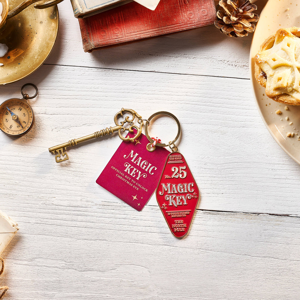 Keychain with 'Magic Key' tags on a wooden surface with a book and pastry.